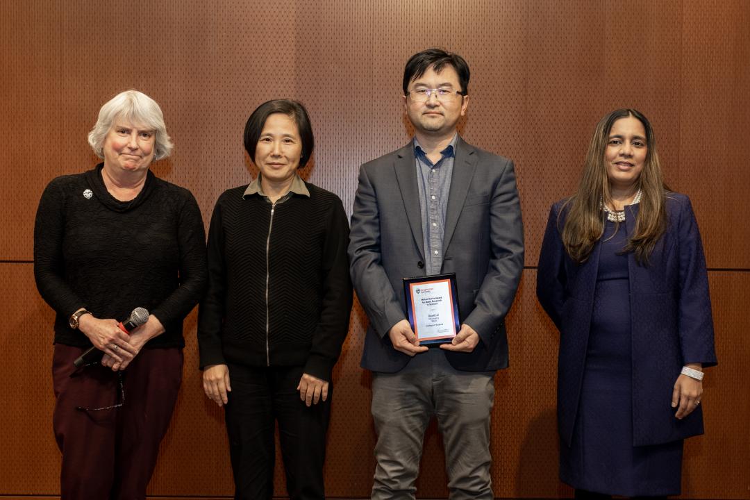 Four individuals pose for a picture. David Ji holds an award. 