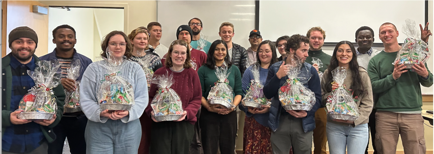Group of students standing together, smiling and holding gift baskets filled with assorted items.
