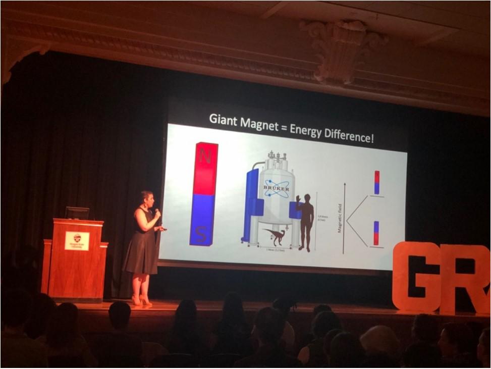 Woman giving speech and pointing to presentation.