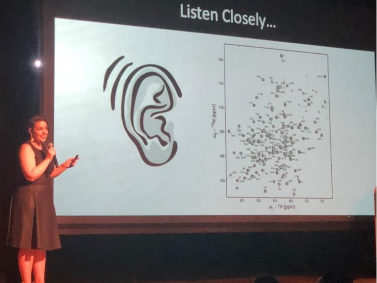 Woman giving speech and pointing to presentation.