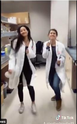 Two women in lab coats dancing.
