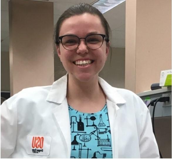 Woman in lab coat smiling at camera.