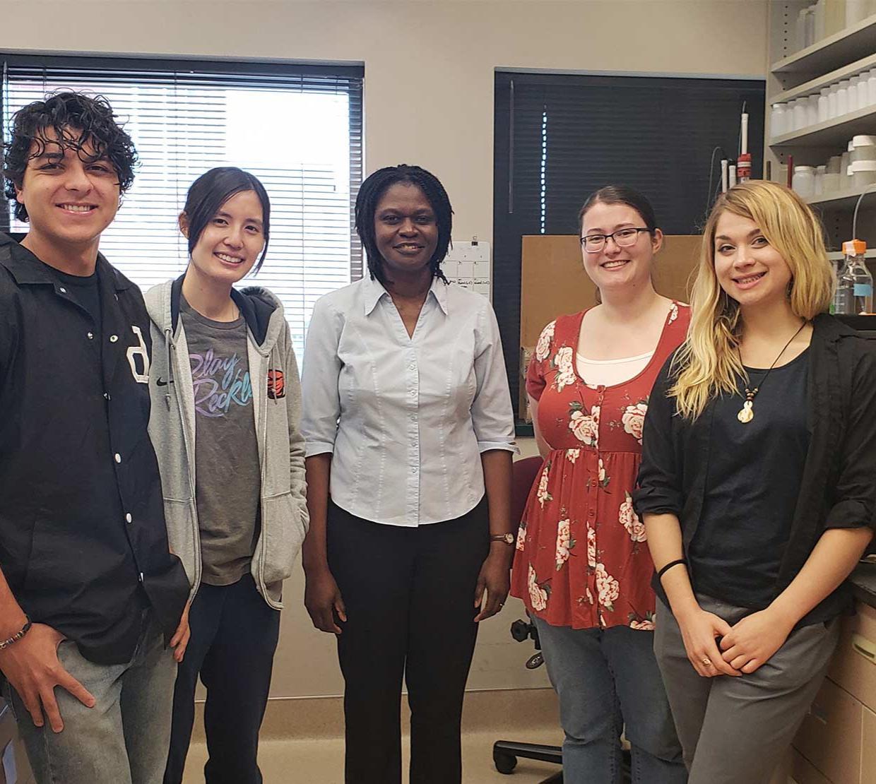 Woman and students smiling at camera.