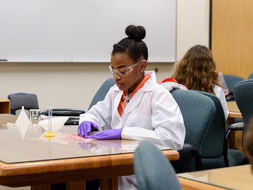 A middle school student working with lab materials in a classroom.