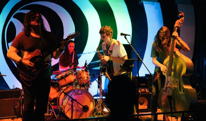 A group of musicians perform on a stage with instruments.